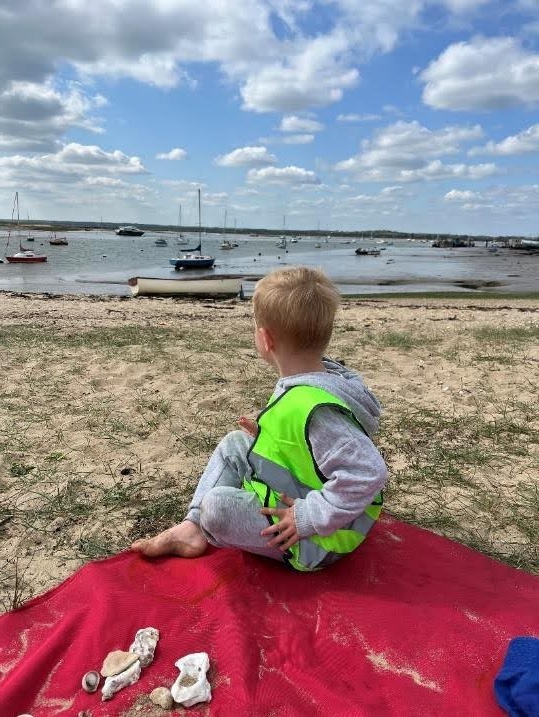 Child on beach looking at boats