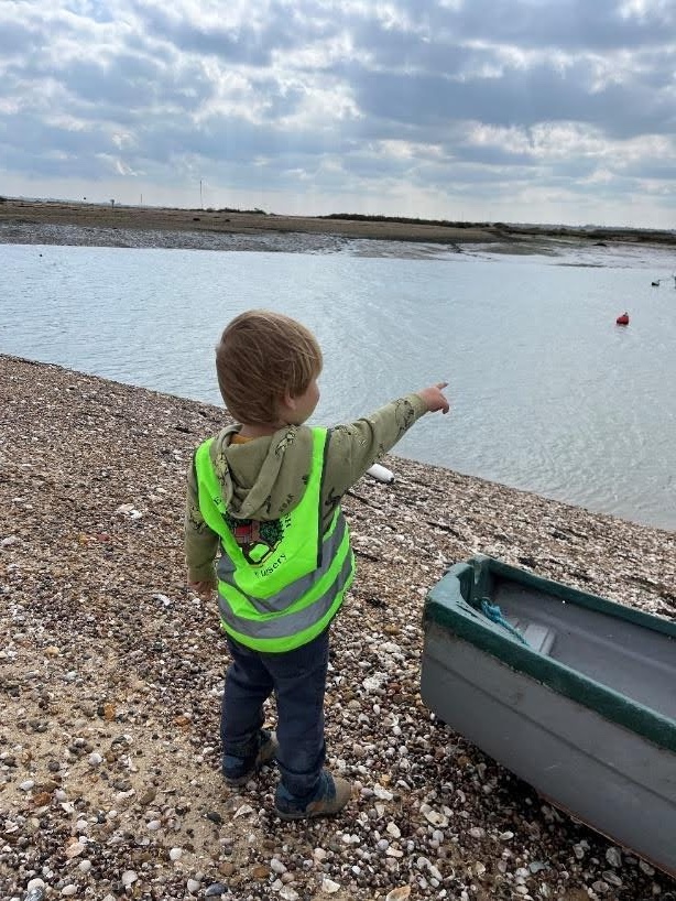Child pointing at water on beach